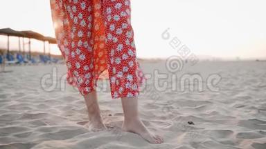 日落时分，站在沙滩上的身着<strong>红色礼服</strong>的女子双腿特写镜头